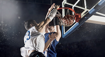 Two basketball players jump at the hool